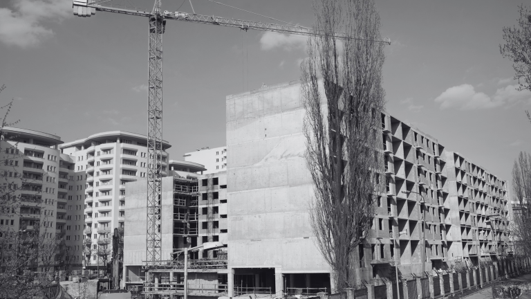 Widok na budowę bloków, w tle żuraw budowlany.